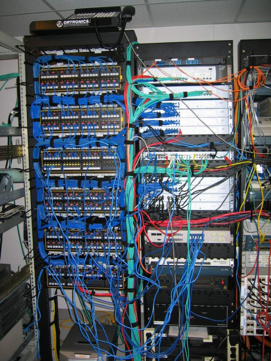 Dense bundles of network patch cables running into switches in a server room rack